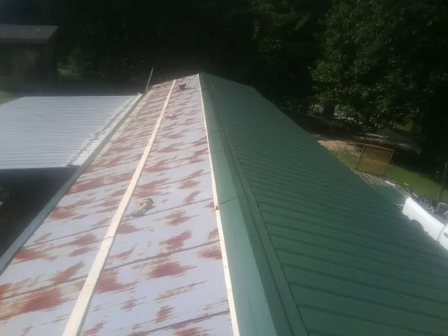Old rusted panels beside newly installed green metal roofing — Wind Damage Roof Repair by Roofing Brothers in Wallace