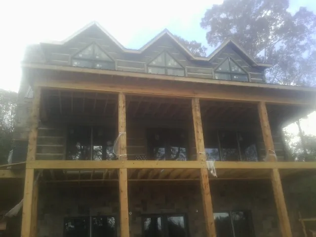 Dormers and porch framing on a large log home under construction — Roof Coating work by our crew in Wallace