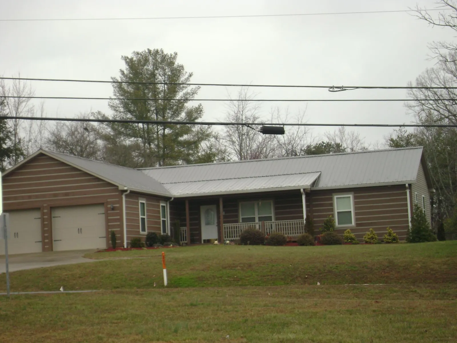 Gray metal roof on a log sided ranch home with a front porch in Wallace